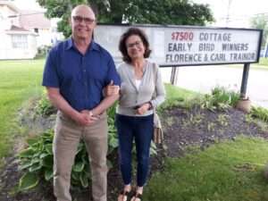Florence & Carl Trainor, our $7500 Winners standing in front of the sign in front of our office